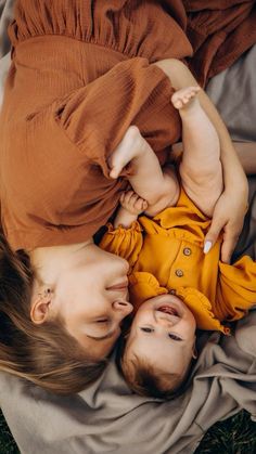 two young children laying on top of each other with their hands around the baby's head