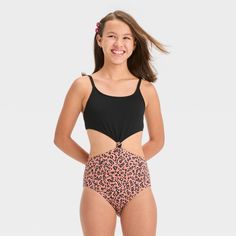 Add on-trend flair to your kid's swim closet with the "In Her Element" Leopard Spots One-Piece Swimsuit from art class™. This black one-piece swimsuit features a sleeveless upper that joins the leopard-print bottom with a knot for a stylish look. Providing four-way stretch and modest coverage, this sleeveless swimsuit makes a comfy pick for watery adventures, and comes with adjustable straps. Plus, they'll stay shielded from sun rays with the UPF 50+ rated fabric. Welcome to art class™, where st Trendy Black Tankini For Swimming, Playful Black Swimwear For The Beach, Playful Black Swimwear For Beach Season, Black Summer Beachwear Swimwear, Black Stretch Swimwear For Play, Sleeveless Swimsuit, Black One Piece Swimsuit, 1 Piece Swimsuit