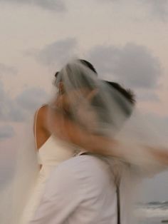 a blurry photo of a bride and groom hugging on the beach at sunset or sunrise