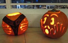 two carved pumpkins sitting next to each other on a tile floor with city lights in the background