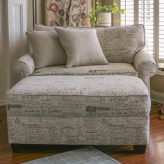 a couch sitting in front of a window next to a rug