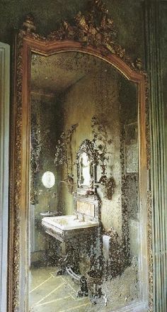 an ornate mirror in the middle of a room with a sink and mirror on it