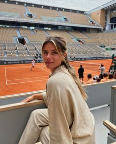 a woman sitting on a bench in front of a tennis court