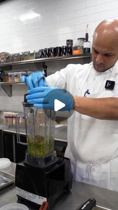 a man wearing blue gloves is making something in a blender