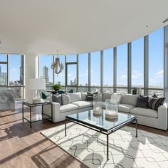 a living room filled with furniture and large windows overlooking the cityscape in the distance