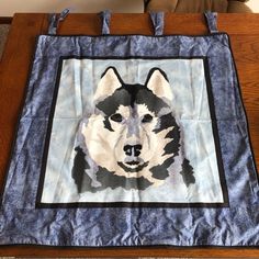 a black and white husky dog on a blue background quilted onto a wooden table