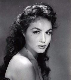 an old black and white photo of a woman with long hair wearing a strapless top