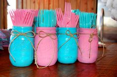 four mason jars with pink and blue hairbrushes in them sitting on a table