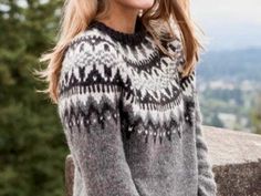 a woman is wearing a sweater and posing for the camera with trees in the background