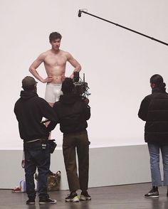 a man with no shirt standing in front of a camera