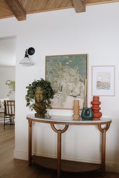 a table with vases and pictures on the wall