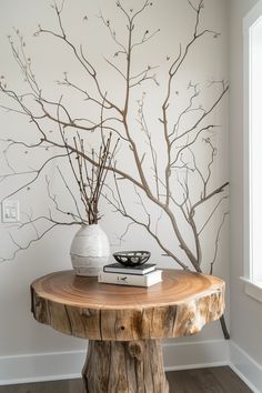 a wooden table topped with a white vase filled with flowers next to a tree branch