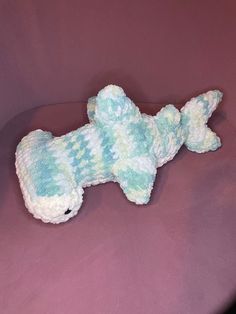 a blue and white dog toy laying on top of a purple couch