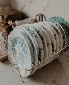 a rack filled with plates sitting on top of a counter next to a basket full of dishes