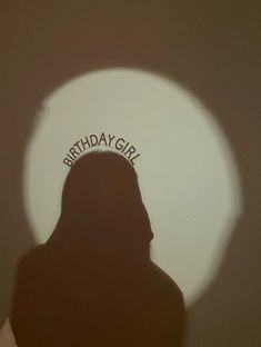 the shadow of a woman's head in front of a circular object that says birthday girl