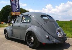 an old vw bug is parked on the side of the road in front of a sign