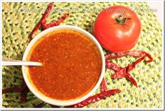 a bowl of chili sauce next to a tomato