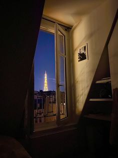 an open window with a view of the eiffel tower lit up at night