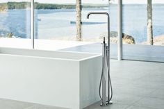 a large bath tub sitting in front of a window next to a sink with a faucet