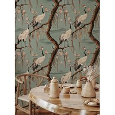 the wallpaper has birds on it and is next to a table with two chairs