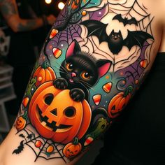 a woman's arm with a black cat and pumpkins on it, surrounded by bats