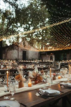 an outdoor dinner table set with candles and place settings