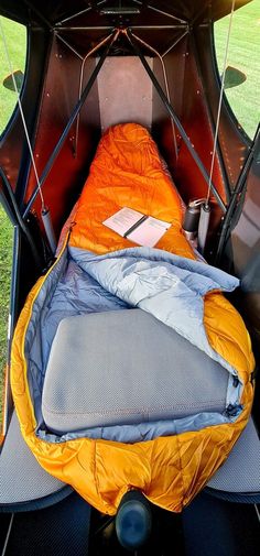 an orange sleeping bag sitting in the back of a truck with it's door open