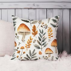 a white pillow with mushrooms and leaves on it sitting on a furnishing area