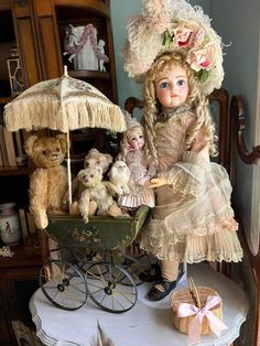 a doll sitting on top of a table next to stuffed animals and a baby carriage