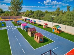 an aerial view of a play area with lots of fake grass and small houses in the middle