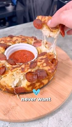 someone is dipping some pizza sauce on top of the small pizza pie with pepperoni and cheese