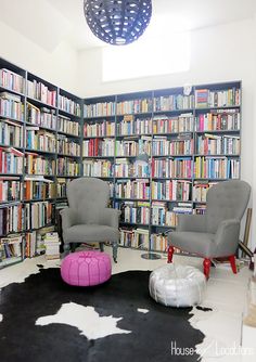 two chairs and a ottoman in front of a bookshelf filled with lots of books