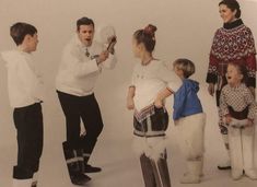 a group of people standing next to each other in front of a white wall holding balloons