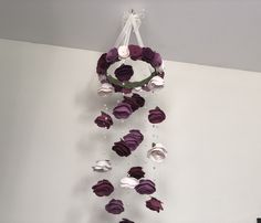 a purple and white flowered mobile hanging from the side of a wall in a room