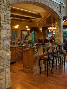 an open kitchen and dining area with stone arches in the center, along with hardwood floors