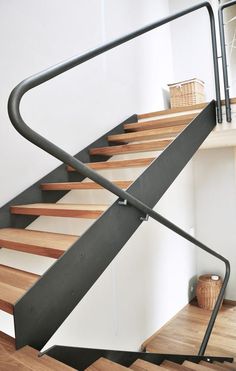 there is a metal railing on the bottom of a stair case in a house with wood floors and white walls