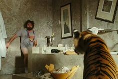 a man standing in front of a bathroom mirror with a tiger on it's side