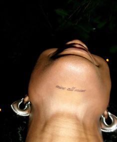 the back of a woman's head with tattoos on her left side and words written in cursive font