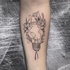 a tattoo on the leg of a woman with flowers around her and a light bulb