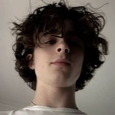 a young man with curly hair looking at the camera