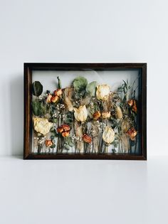 an arrangement of dried flowers in a shadow box