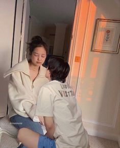 two young women sitting on the floor in front of a mirror looking at each other