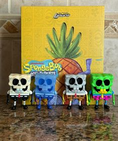 five small toy figures sitting on top of a counter next to a box with a pineapple