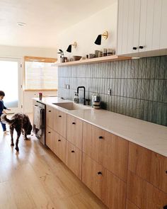 a young boy and his dog are in the kitchen looking at something on the counter