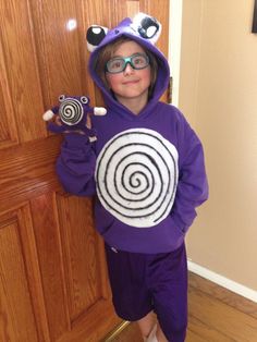 a young boy wearing glasses and a purple hoodie holding a lollipopo