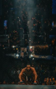 a man kneeling down in the middle of a wrestling ring with his hands on his knees