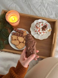 a tray with cookies, marshmallows and chocolate on it next to a candle