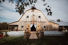 a barn with chairs and tables set up for an outdoor wedding in front of it