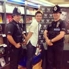 three police officers are standing in front of a book shelf with books and magazines on it