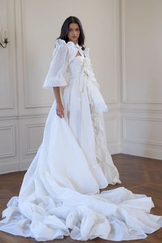 This luxury topper, crafted from crisp silk organdy reminiscent of 1930s haute couture, fastens effortlessly at your waist, transforming any bridal dress into an extravagant gown. Adorned with delicate ruffles that shimmer with each step, it cascades into a sweeping train, the organdy's airy yet structured nature allowing it to float gracefully behind you. Glide down the aisle in full bridal splendour, then detach the tournure to dance freely under the crystal chandeliers. Organdy open-front ski Rooftop Reception, Picturesque Garden, Open Front Skirt, Silk Dressing Gown, Corset Skirt, Puff Dress, Crystal Chandeliers, Dresses Elegant, Knitted Coat